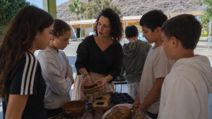 Una docente muestra objetos tradicionales canarios a varios escolares en una actividad educativa en Mogán.